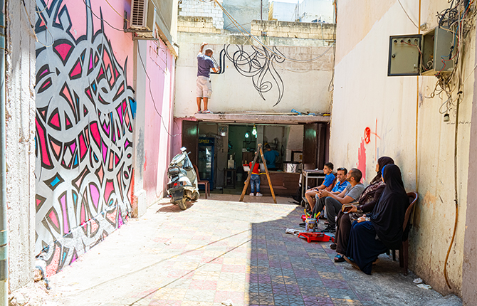 eL Seed painting above a cafeteria, next to 'The Olive Tree' mural inside Ain Al Hilweh